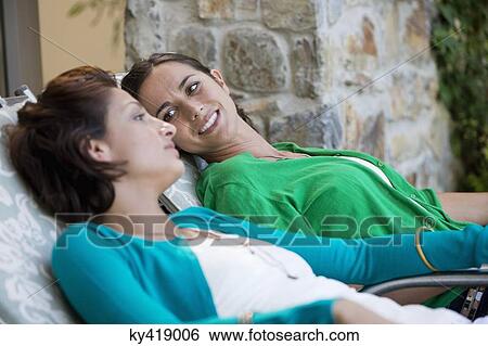 Two women relaxing on lounge chairs View Large Photo Image Stock Photograph - Two women relaxing on lounge chairs. Fotosearch