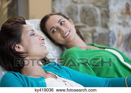 Stock Photograph - Two women relaxing on lounge chairs. Fotosearch