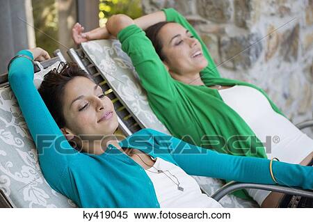 Two women relaxing on lounge chairs View Large Photo Image Stock Photography - Two women relaxing on lounge chairs. Fotosearch