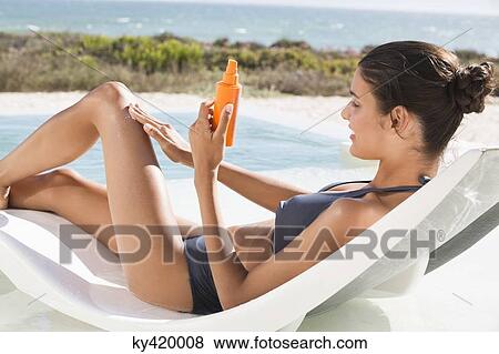 Beautiful woman applying suntan lotion while sunbathing on the beach View Large Photo Image Stock Photo - Beautiful woman applying suntan lotion while sunbathing on the beach. Fotosearch