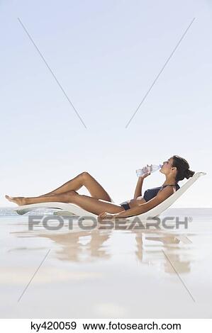 Beautiful woman drinking water on the beach View Large Photo Image Stock Photo - Beautiful woman drinking water on the beach. Fotosearch