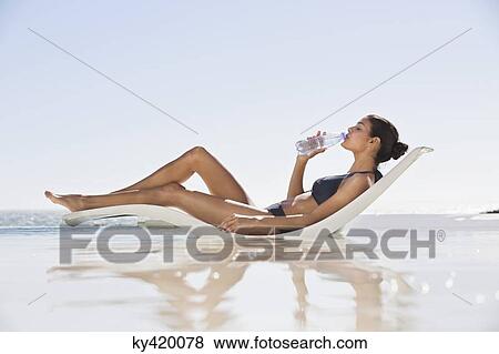 Beautiful woman drinking water on the beach View Large Photo Image Stock Photo - Beautiful woman drinking water on the beach. Fotosearch