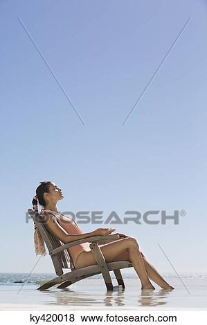 Beautiful woman sitting on a chair on the beach View Large Photo Image Stock Photo - Beautiful woman sitting on a chair on the beach. Fotosearch