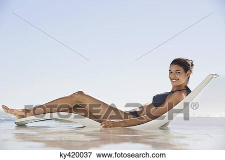Stock Photo - Beautiful woman sunbathing on the beach. Fotosearch