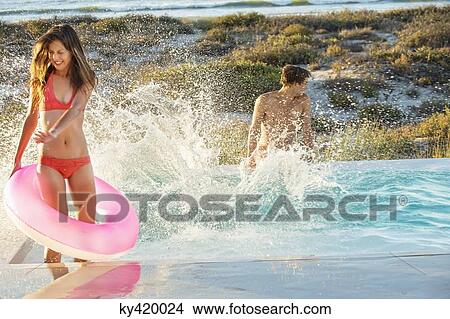 Couple enjoying in a swimming pool on the beach View Large Photo Image Picture - Couple enjoying in a swimming pool on the beach. Fotosearch