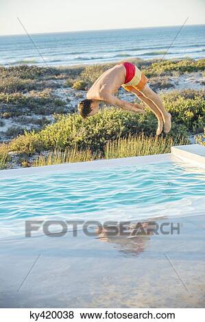 Man diving into a pool near the sea View Large Photo Image Stock Photo - Man diving into a pool near the sea. Fotosearch