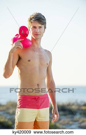 Man holding a rubber duck on the beach View Large Photo Image Stock Photo - Man holding a rubber duck on the beach. Fotosearch