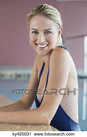 Stock Image - Woman leaning at the edge of a swimming pool. Fotosearch