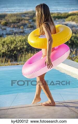 Woman standing with inflatable rings at the poolside View Large Photo Image Stock Image - Woman standing with inflatable rings at the poolside. Fotosearch