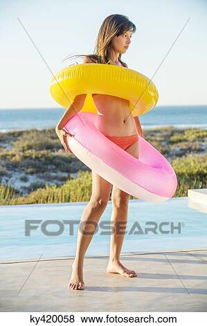 Woman standing with inflatable rings at the poolside View Large Photo Image Stock Photo - Woman standing with inflatable rings at the poolside. Fotosearch