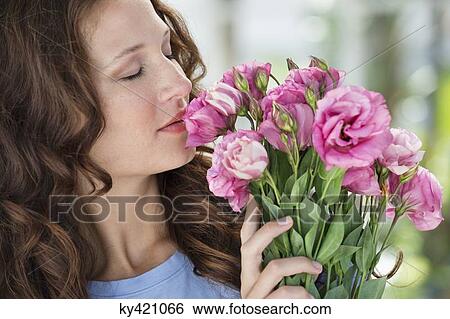 Close-up of a woman smelling flowers View Large Photo Image Stock Photograph - Close-up of a woman smelling flowers. Fotosearch