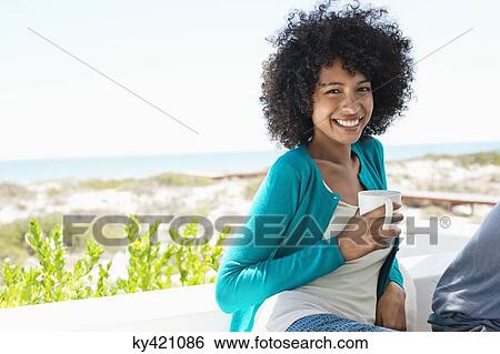 Stock Photograph - Portrait of a smiling woman drinking coffee. Fotosearch