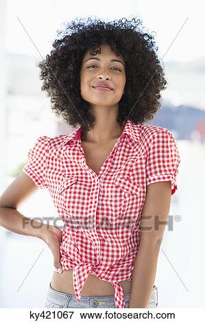 Stock Photo - Portrait of a smiling woman standing with hand on hip. Fotosearch