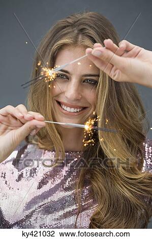 Woman celebrating with sparkler and smiling View Large Photo Image Stock Image - Woman celebrating with sparkler and smiling. Fotosearch