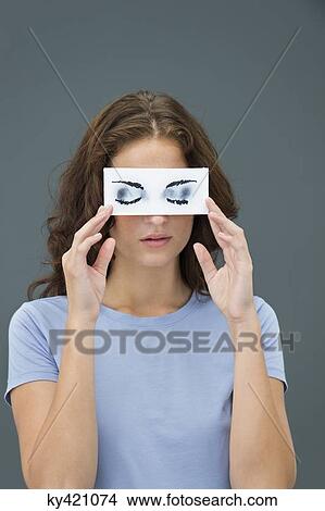 Picture - Woman hiding behind paper with false eyes. Fotosearch