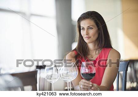 Woman holding a wine glass and thinking in a restaurant View Large Photo Image Stock Image - Woman holding a wine glass and thinking in a restaurant. Fotosearch