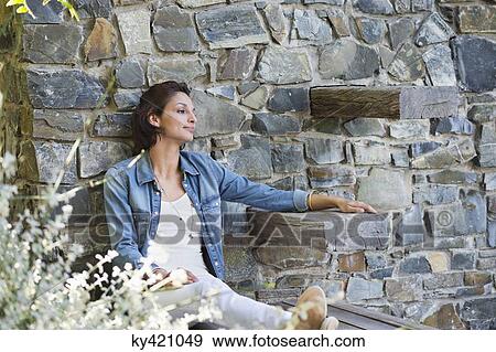 Woman leaning against a stone wall and day dreaming View Large Photo Image Stock Photo - Woman leaning against a stone wall and day dreaming. Fotosearch