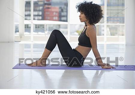 Stock Photograph - Woman practicing yoga on an exercise mat. Fotosearch
