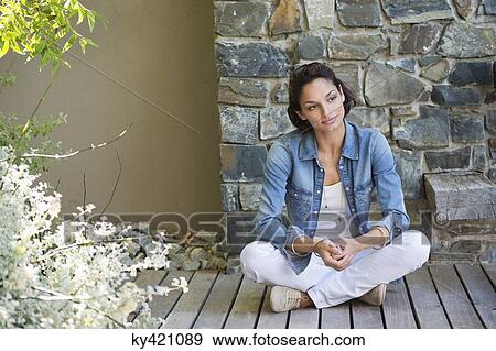 Stock Photo - Woman sitting on a hardwood floor and day dreaming. Fotosearch