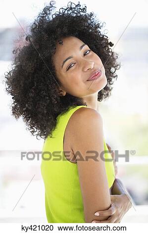Stock Image - Woman standing with her arms crossed and smiling. Fotosearch