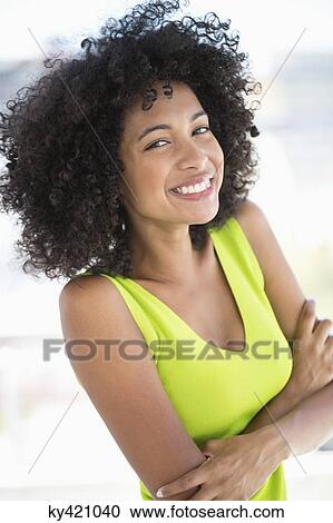 Woman standing with her arms crossed and smiling View Large Photo Image Stock Image - Woman standing with her arms crossed and smiling. Fotosearch