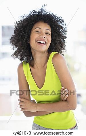 Stock Image - Woman standing with her arms crossed and smiling. Fotosearch