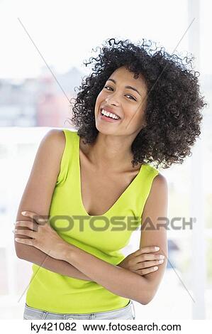 Stock Image - Woman standing with her arms crossed and smiling. Fotosearch