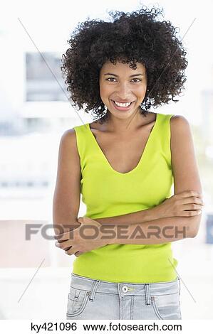 Stock Photograph - Woman standing with her arms crossed and smiling. Fotosearch