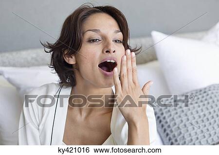 Stock Photograph - Woman yawning on the bed. Fotosearch