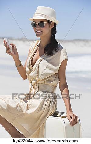 Beautiful woman text messaging on a cell phone on the beach View Large Photo Image Picture - Beautiful woman text messaging on a cell phone on the beach. Fotosearch