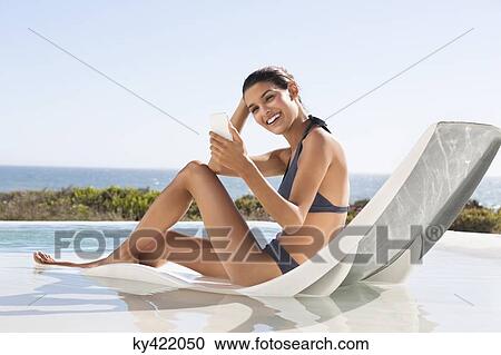 Beautiful woman video calling on cell phone while sunbathing on the beach View Large Photo Image Stock Image - Beautiful woman video calling on cell phone while sunbathing on the beach. Fotosearch