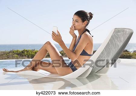 Beautiful woman video calling on cell phone while sunbathing on the beach View Large Photo Image Stock Image - Beautiful woman video calling on cell phone while sunbathing on the beach. Fotosearch