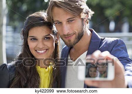 Couple taking picture of themselves with a mobile phone View Large Photo Image Stock Photo - Couple taking picture of themselves with a mobile phone. Fotosearch