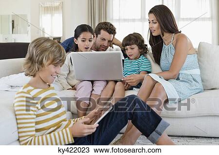 Family using electronic gadgets in a living room View Large Photo Image Stock Image - Family using electronic gadgets in a living room. Fotosearch