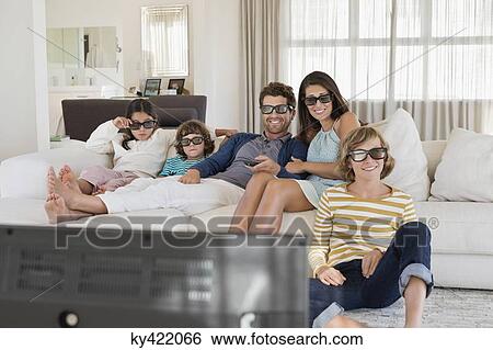 Stock Photograph - Family watching television at home while wearing 3D glasses. Fotosearch