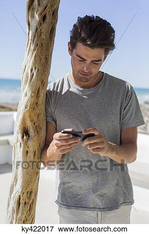 Stock Photo - Man reading text message on a mobile phone. Fotosearch