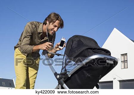 Man showing mobile phone to a baby in stroller View Large Photo Image Stock Photo - Man showing mobile phone to a baby in stroller. Fotosearch