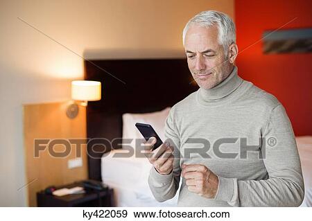Stock Photo - Man using a cell phone in a hotel room. Fotosearch
