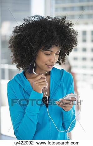 Smiling woman listening to music on a mobile phone View Large Photo Image Stock Image - Smiling woman listening to music on a mobile phone. Fotosearch