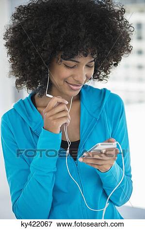 Smiling woman listening to music on a mobile phone View Large Photo Image Stock Photo - Smiling woman listening to music on a mobile phone. Fotosearch