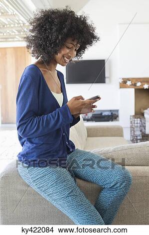 Smiling woman text messaging on a mobile phone View Large Photo Image Picture - Smiling woman text messaging on a mobile phone. Fotosearch