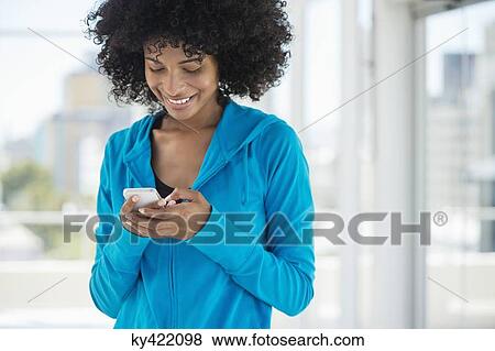 Stock Photo - Smiling woman text messaging on a mobile phone. Fotosearch
