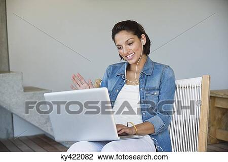Stock Image - Woman doing online chatting on a laptop. Fotosearch