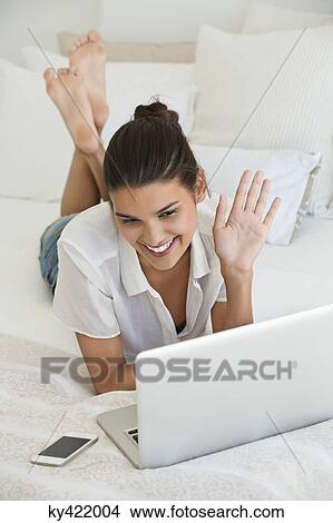 Picture - Woman having online video chat on a laptop. Fotosearch