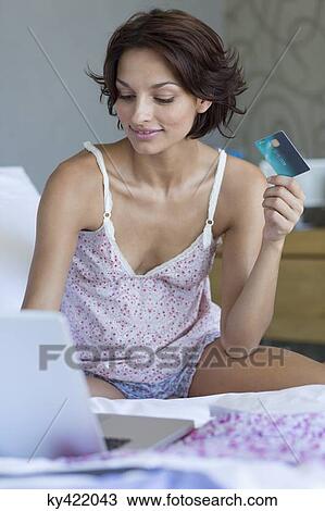 Woman holding credit card and working on a laptop View Large Photo Image Stock Image - Woman holding credit card and working on a laptop. Fotosearch
