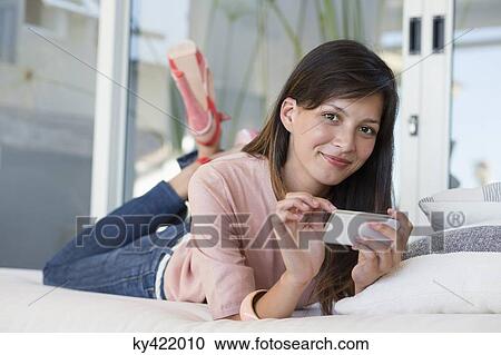 Woman lying on the bed using mobile phone View Large Photo Image Stock Image - Woman lying on the bed using mobile phone. Fotosearch