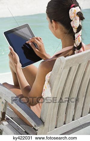 Woman sitting on a chair and using digital tablet on the beach View Large Photo Image Stock Image - Woman sitting on a chair and using digital tablet on the beach. Fotosearch