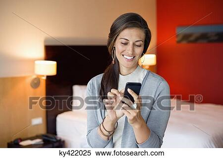 Woman using a cell phone in a hotel room View Large Photo Image Stock Photography - Woman using a cell phone in a hotel room. Fotosearch