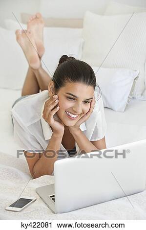 Woman using a laptop on the bed View Large Photo Image Stock Image - Woman using a laptop on the bed. Fotosearch