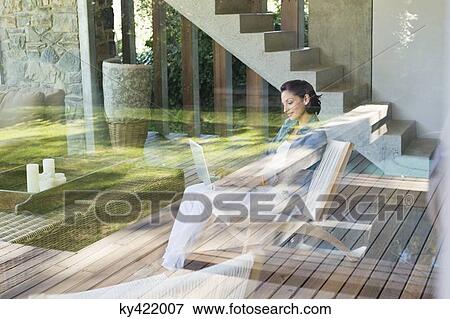 Woman using a laptop viewed through from a glass wall View Large Photo Image Stock Photo - Woman using a laptop viewed through from a glass wall. Fotosearch